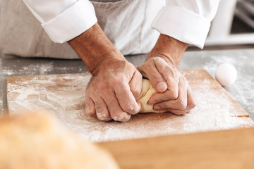 Closeup portrait of caucasian male hands mixing dough for pastry, on table at bakery or kitchen