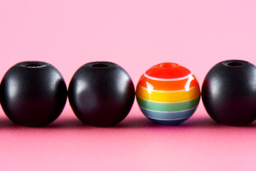 LGBT concept. Many black balls and one painted in the colors of the rainbow.