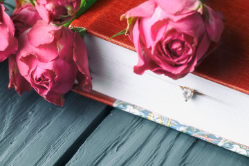 delicate roses on a book with a ring