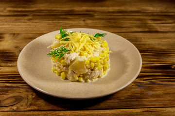 Festive salad with chicken breast, sweet corn, canned pineapple, cheese and mayonnaise on wooden table