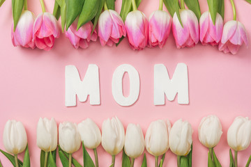 pink and white tulips arranged in rows with paper word mom in center on pink background