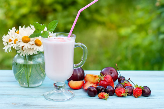 yogurt in a glass goblet and berries on a wooden table in the summer garden. Healthy food