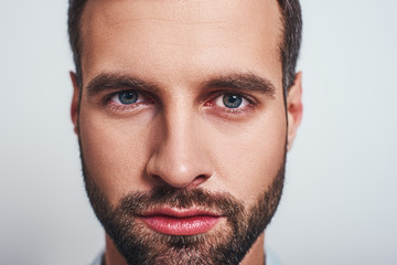 Close-up studio portrait of handsome guy with stubble looking at camera