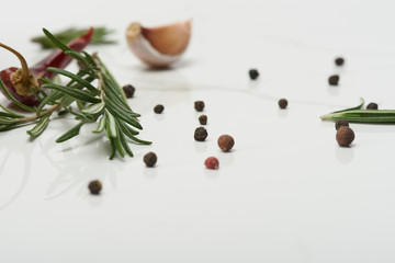 rosemary leaves, garlic clove, black pepper and red hot chili peppers on white surface