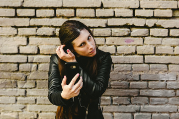 Young girl using the screen of her mobile phone as a mirror to put on makeup and remove pimples from her face, and she gets pretty for a date with her boyfriend.