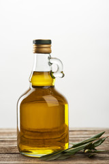 bottle of oil and olive tree leaves  isolated on grey