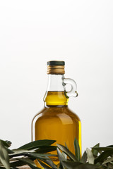 bottle of oil and olive tree leaves isolated on grey