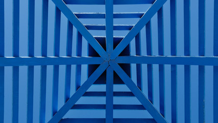 Symmetrical pattern obtained from a blue patio wooden cover or a pergola with a roof against clear...