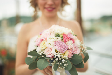 Bride holding big wedding bouquet on ceremony with perfect landscape