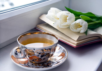 Cup of tea on the windowsill, book, 3 white tulips