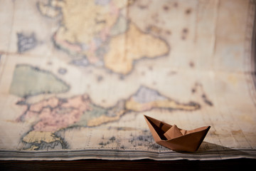 Selective focus of map and paper boat on wooden table