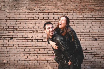 Fototapeta na wymiar Girl riding on the back of her boyfriend laughing and having fun together as they look young and happy.