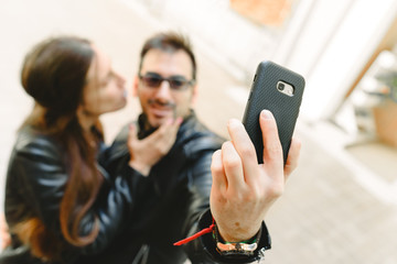Young couple in love making a selfie on the street posing as amateur models.
