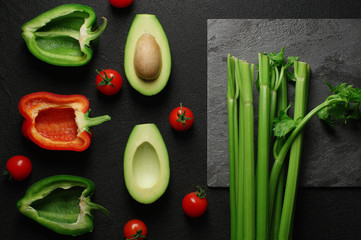 Healthy food clean eating selection on gray background. Green and red bell pepper, avocado, celery and tomatoes. Top view