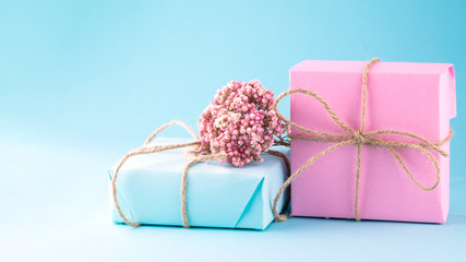 Obraz na płótnie Canvas two gift boxes of pink and blue decorated with flowers on a blue background. 