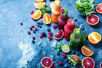 Different smoothie in bottles, detox vitamin drink with berries and fruits
