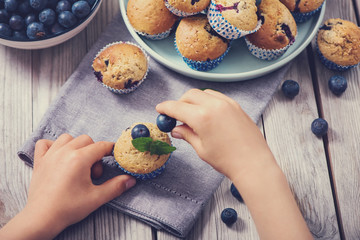 Child´s hands holding blueberry muffins, healthy homemade dessert with berries, baking with child