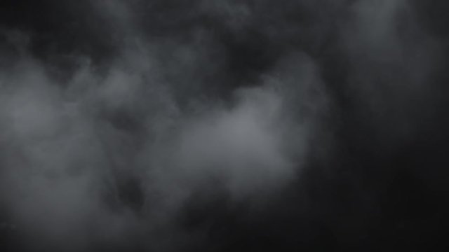 Atmospheric smoke VF overlay element. Haze background. Smoke in slow motion on black background. White smoke slowly floating through space against black background. Mist effect. Fog effect.