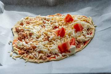 Homemade raw pizza with tuna and tomato