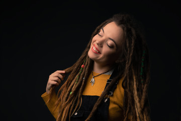 Fototapeta premium Portrait of a young girl with dreads on black background. Studio shoot.