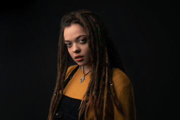 Fototapeta premium Portrait of a young girl with dreads on black background. Studio shoot.
