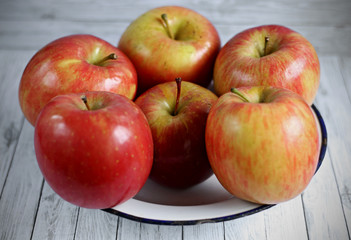 Fresh red apples on white wooden background