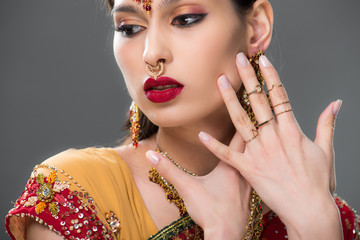elegant indian woman in sari and accessories, isolated on grey