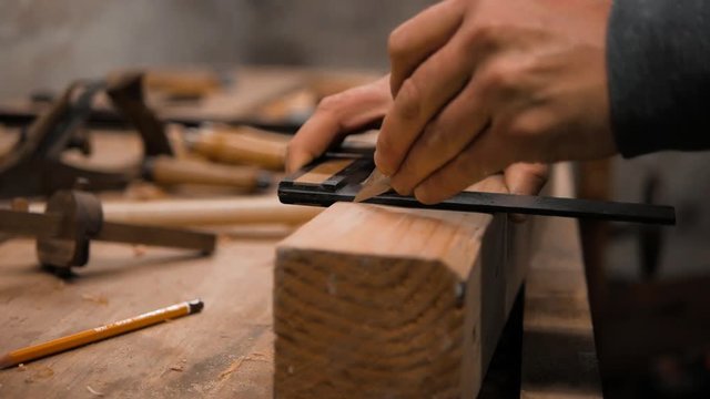 carpenter marks the workpiece with a square and marking knife