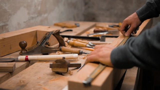 carpenter marks the workpiece with a tape measure and a pencil