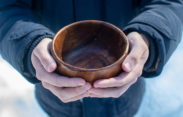 Men hand holding empty wooden bowl