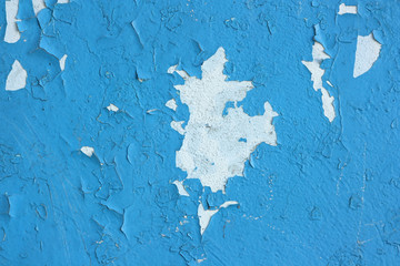 Peeling blue paint on the old wall is like a white spot of arbitrary shape.