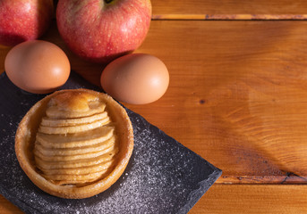 homemade apple pie on a wooden table with fruit in the background