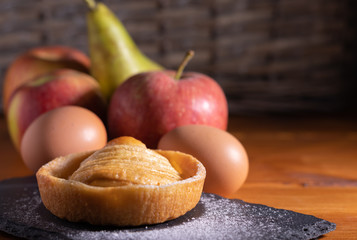 homemade apple pie on a wooden table with fruit in the background