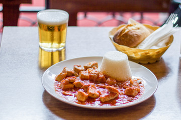 prepared table in a restaurant with rice, meat, beer and bread