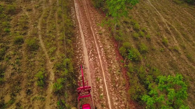 Aerial shot as flying over people unloading coyol palms from trailer to plant them on the field for oil production