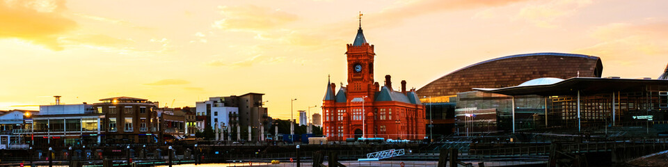 Fototapeta na wymiar Waterfront at night in Cardiff, UK. Sunset colorful sky with Wales Millennium Center