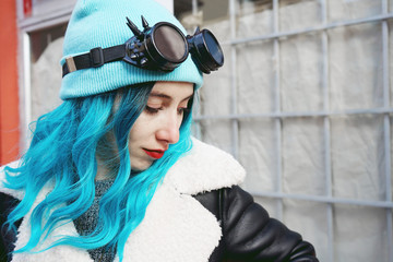 Portrait of a punk or gothic young woman with blue colored hair and wearing black steampunk glasses...