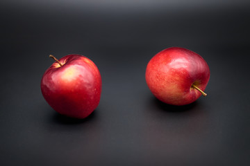 Two red apples on black background