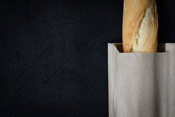 Fresh french roll baked crunchy baguette bread on dark background. Closeup of crust of bread food...