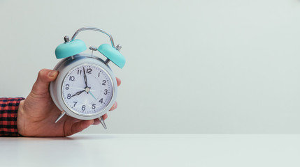 Retro styled white alarm clock in man’s hand, isolated