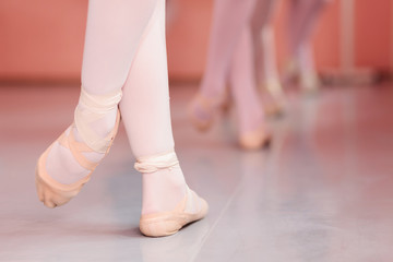 Close-up of teenage ballerina's feet, practicing ballet moves in a dancing studio. Low angle view,...