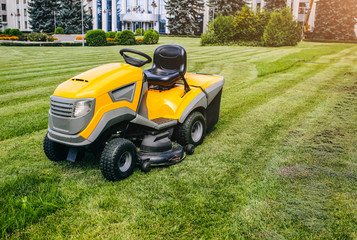 Grass cutter in the work.  Machine for cutting lawn is standing outdoors. Summer bright photo.