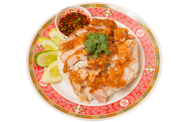 Fried chicken place on top the rice with cucumbers and sauce.