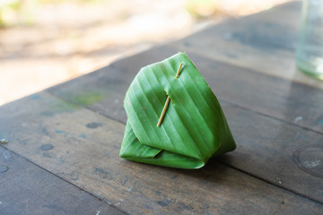 Thai sticky rice with custard in banana leaf on wooden floor