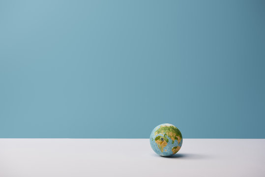 small globe on white table and blue background