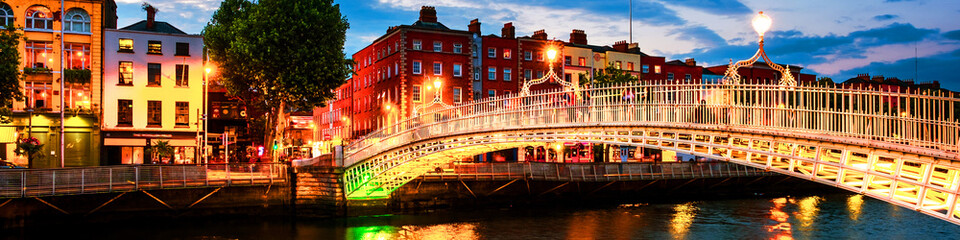 Night view of famous illuminated Ha Penny Bridge in Dublin, Ireland at sunset