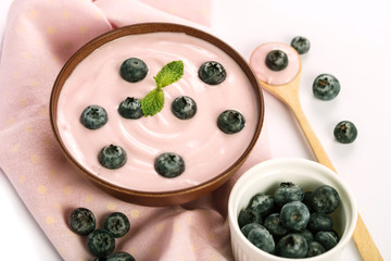 close up a pink creamy homemade blueberries fruit yogurt with fresh green mint leaf on wooden table background