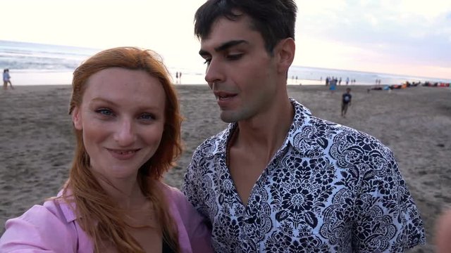 Happy couple taking selfie photos, recording video on beach, super slow motion