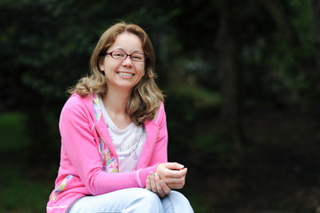 Obraz premium Beautiful mixed race young woman (Brazilian / Japanese) with glasses, happy and looking forward. Green blurred background. Space for text.