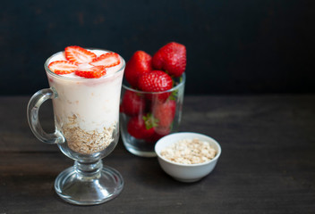 Milk shake with strawberries or breakfast with muesli and yogurt and berries on a dark background